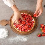 Donna decora crostata con fragole fresche