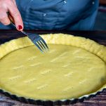 Donna buca il fondo della frolla con la forchetta