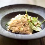 Risotto with gem fit and levisticum celery on a wood table composition