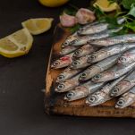 Sarde fresche e crude sul tagliere con limone