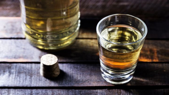 Bicchierino con liquore con bottiglia di vetro su tavolo di legno
