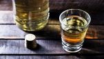 Bicchierino con liquore con bottiglia di vetro su tavolo di legno