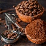 Ceramic bowl with coffee beans and ground coffee on a wooden background