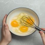 Donna in cucina che sbatte le uova