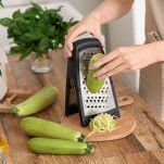 Donna grattugia le zucchine in cucina
