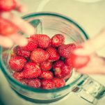 Mani di donna mettono fragole nel frullatore