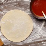 Raw Pizza Base And Ketchup. Rolled Out Dough