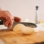 Mani tagliano con il coltello la scamorza