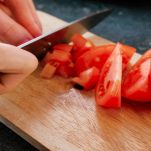 Mani tagliano i pomodori a spicchi