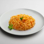 Plate of risotto with pumpkin isolated on white table