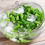 Colander with raw green bean on a table