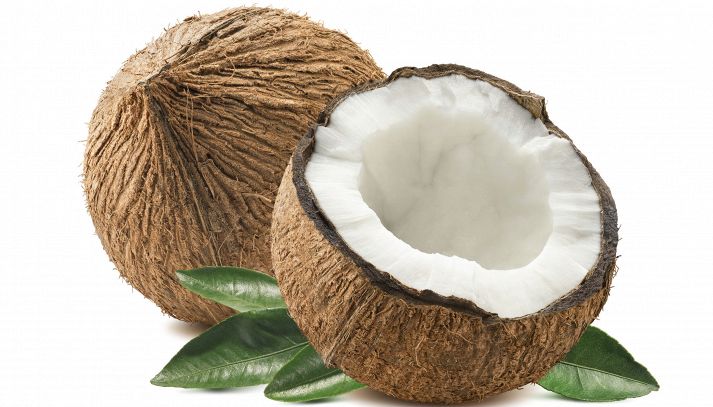 Davanti una metà di noce di cocco, con polpa bianca e scorza marrone; dietro una drupa intera e foglie della palma. Il tutto su uno sfondo bianco latte