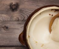 Una scodella di terracotta di forma rotonda colma di strutto bianco tendente al panna; vi è affondato un cucchiaio di legno chiaro; il piano è in legno