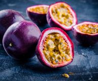 Frutti della passione tagliati a metà: la scorza è lucente e di colore viola intenso, l’interno ricco di semi rotondi e collosi in una polpa giallo-aranciata
