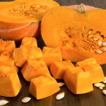 Una zucca mantovana tagliata a metà e alcuni pezzi più piccoli; la polpa è arancione intenso, consistente e dolciastra, pronta per essere cucinata