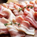 Numerose fette di pancetta tesa le une accanto alle altre; la parte lipidica, di colore bianco latte, si alterna alla parte più proteica, quasi rossa