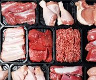 Inquadratura dall'alto di diverse tipologie di carne rossa e bianca in confezioni nere: cosce, sovracosce, tritata, costine, petti...