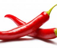 Su sfondo bianco, due peperoncini freschi della varietà jalapegno; il colore è rosso scarlatto tendente al carminio, la forma a cornetto sottile e allungata