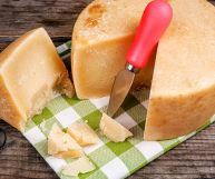 Forma, fetta e scaglie di pecorino stagionato su tovagliolo a quadri e fondo rustico; appoggiato su di esso, il tipico coltello da formaggio