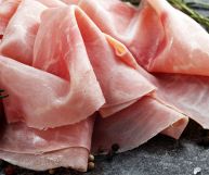 Fette di prosciutto cotto adagiate le une sulle altre e non schiacciate; l’aspetto è invitante e il prodotto fresco; sale grosso e rosmarino su ardesia