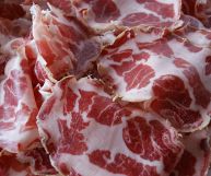 Coppa piacentina appena tagliata, un modo saporito per aprire il pasto: le fette sono caratterizzate da chiazze rosse e bianche-rosate