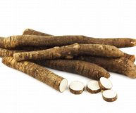 Su sfondo bianco, cinque pezzi interi di scorzonera e uno parzialmente tagliato a rondelle. La pelle è bruna con sfumature più chiare, la polpa bianca