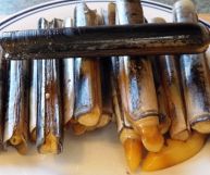 Una pila di cannolicchi cotti disposti verticalmente e adagiati su un piatto; il guscio è di colore giallo con striature brune