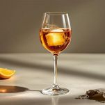 Una zolletta di zucchero scura posata sul fondo di un bicchiere flûte vuoto.