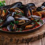 Pentola con cozze al sugo sul tagliere