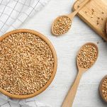 Uncooked green buckwheat grains on white wooden table, flat lay