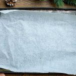 Preparate un grande foglio di carta forno su un’asse di legno o su una superficie resistente, tenendolo ben steso con dei pesi agli angoli per evitare che si arricci.