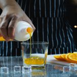 Uomo versa succo d'arancia in un bicchiere di vetro
