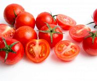 Isolati su fondo bianco, pomodori ciliegini puliti e pronti per essere consumati o cucinati; la polpa è succosa, con semi e buccia rosso brillante