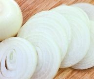 Cipolla bianca tagliate a fettine adagiate su un piano in legno e pronte per essere impiegate in gustose ricette