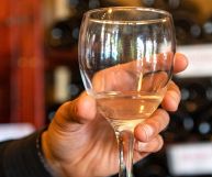 Friuli Isonzo Pinot Grigio DOC, bicchiere su sfondo di bottiglie