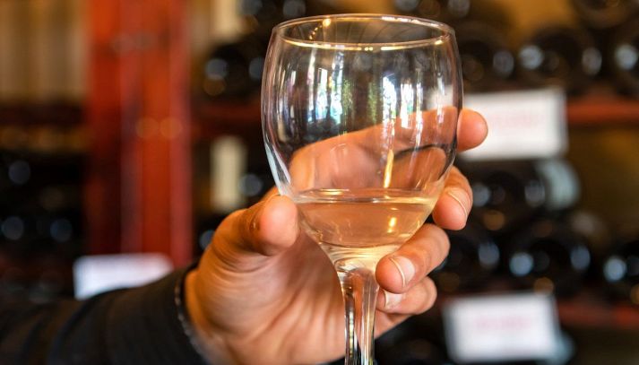 Friuli Isonzo Pinot Grigio DOC, bicchiere su sfondo di bottiglie