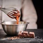 Chef whisking melted chocolate in a mixing bowl
