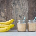 Frullati con banane accanto e legno sullo sfondo