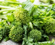 Un mazzo di friarielli freschi, noti anche come broccoli rapa; le infiorescenze, su un tavolo in legno, sono di un bel verde con foglie più scure