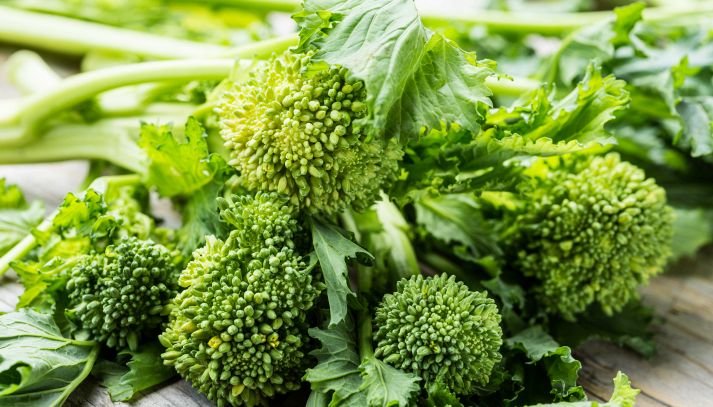 Un mazzo di friarielli freschi, noti anche come broccoli rapa; le infiorescenze, su un tavolo in legno, sono di un bel verde con foglie più scure