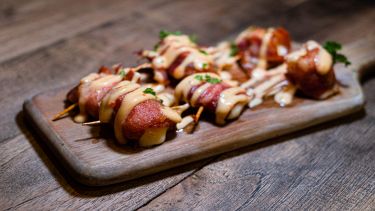 Involtini di pancetta e ananas cosparsi di salsa