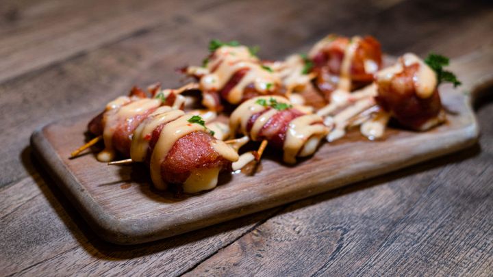 Involtini di pancetta e ananas cosparsi di salsa
