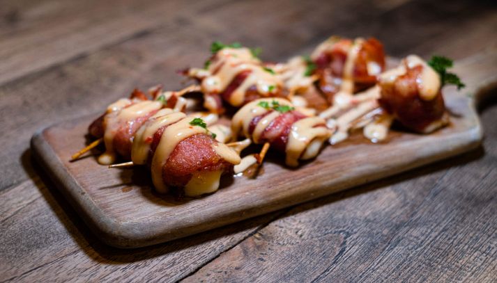Involtini di pancetta e ananas cosparsi di salsa
