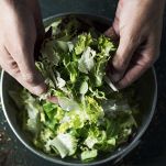 In una grande zuppiera unite l'indivia, le mele e le arance, il mix di scalogni e aglio