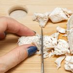 Mani tagliano il petto di pollo cotto sul tagliere