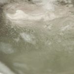 Pentola con acqua e petto di pollo in cottura