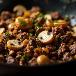 Padella coperta con carne e funghi in cottura.