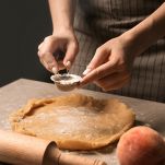 Woman preparing dough for peach galette at table