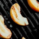 Grilled peach on black gas grill. Grilled dessert.
