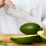 Donna taglia avocado su un tagliere di legno